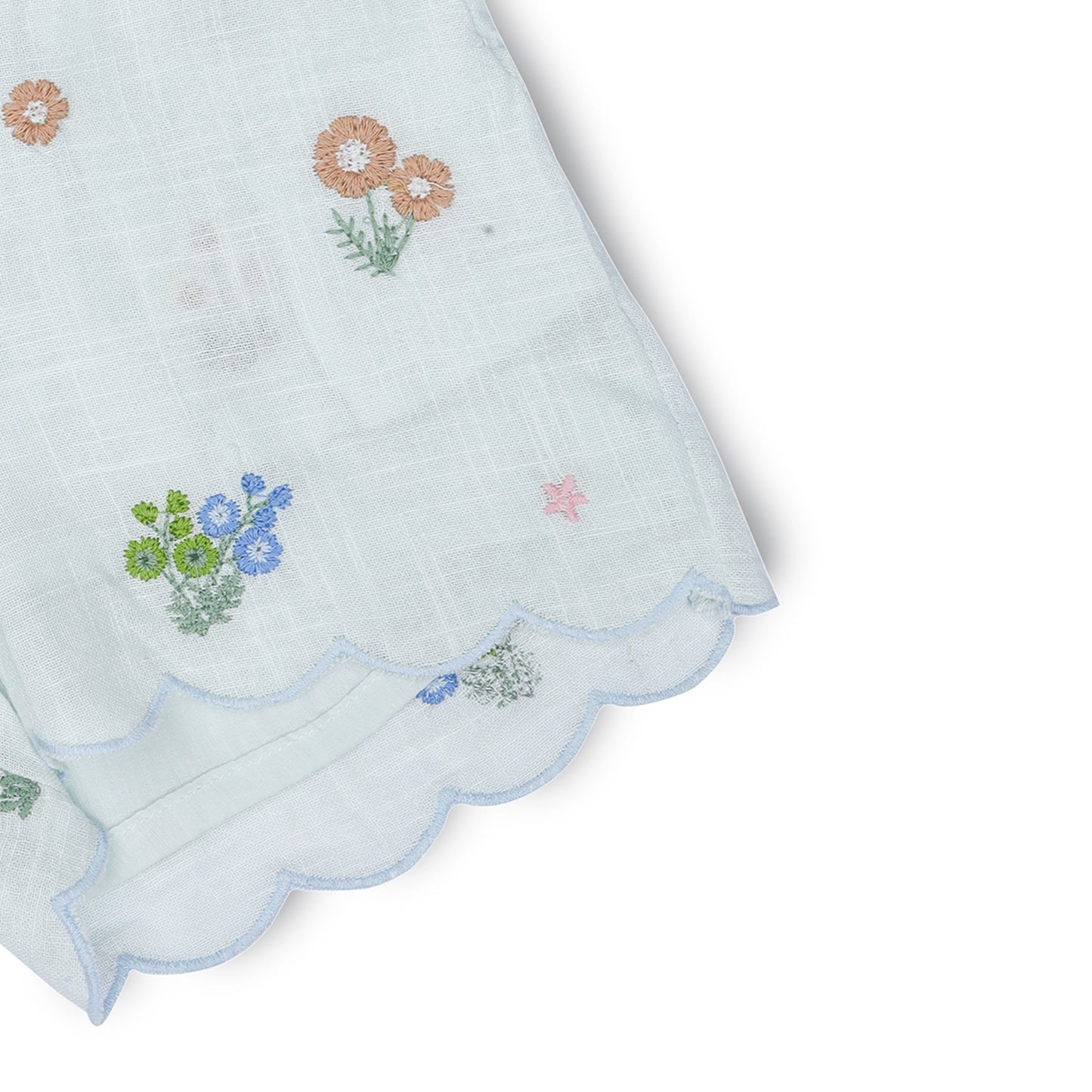Embroidered floral patterns on a white fabric with scalloped edge.
